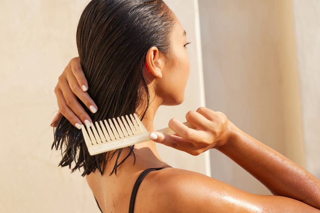 Woman,Combing,Wet,Hair,With,Wooden,Comb,In,Bright,Sunlight,